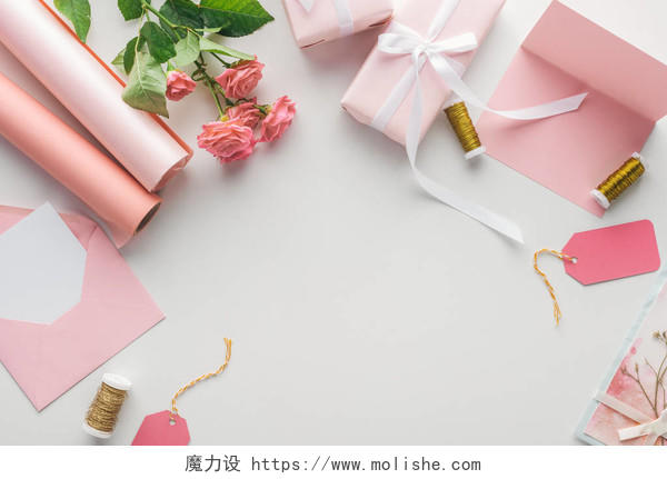 灰色背景上的粉红色玫瑰纸卷包装礼品信封和贺卡的顶视图日记情人节